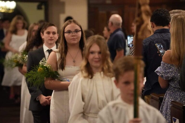 Youth procession holding flowers during a church ceremony, highlighting tradition and community spirit.