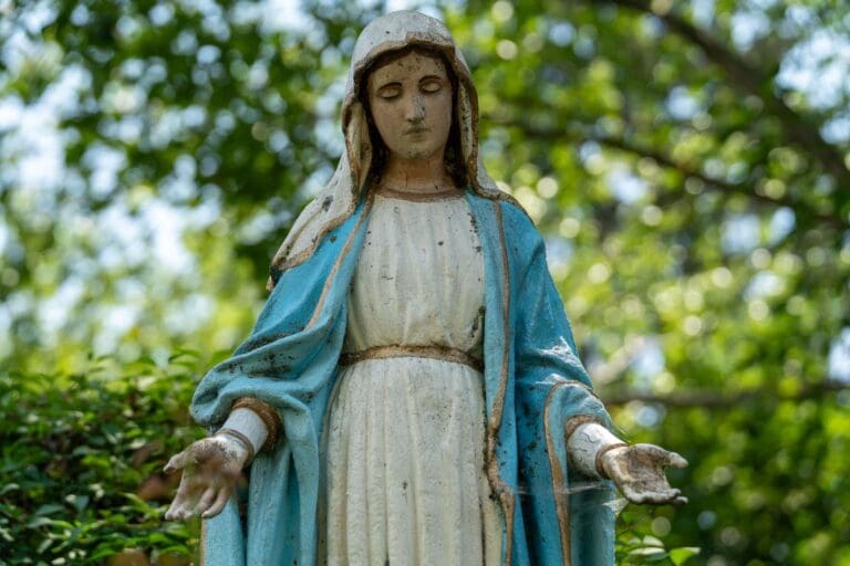 Statue of the Virgin Mary in a garden setting, symbolizing peace and serenity.