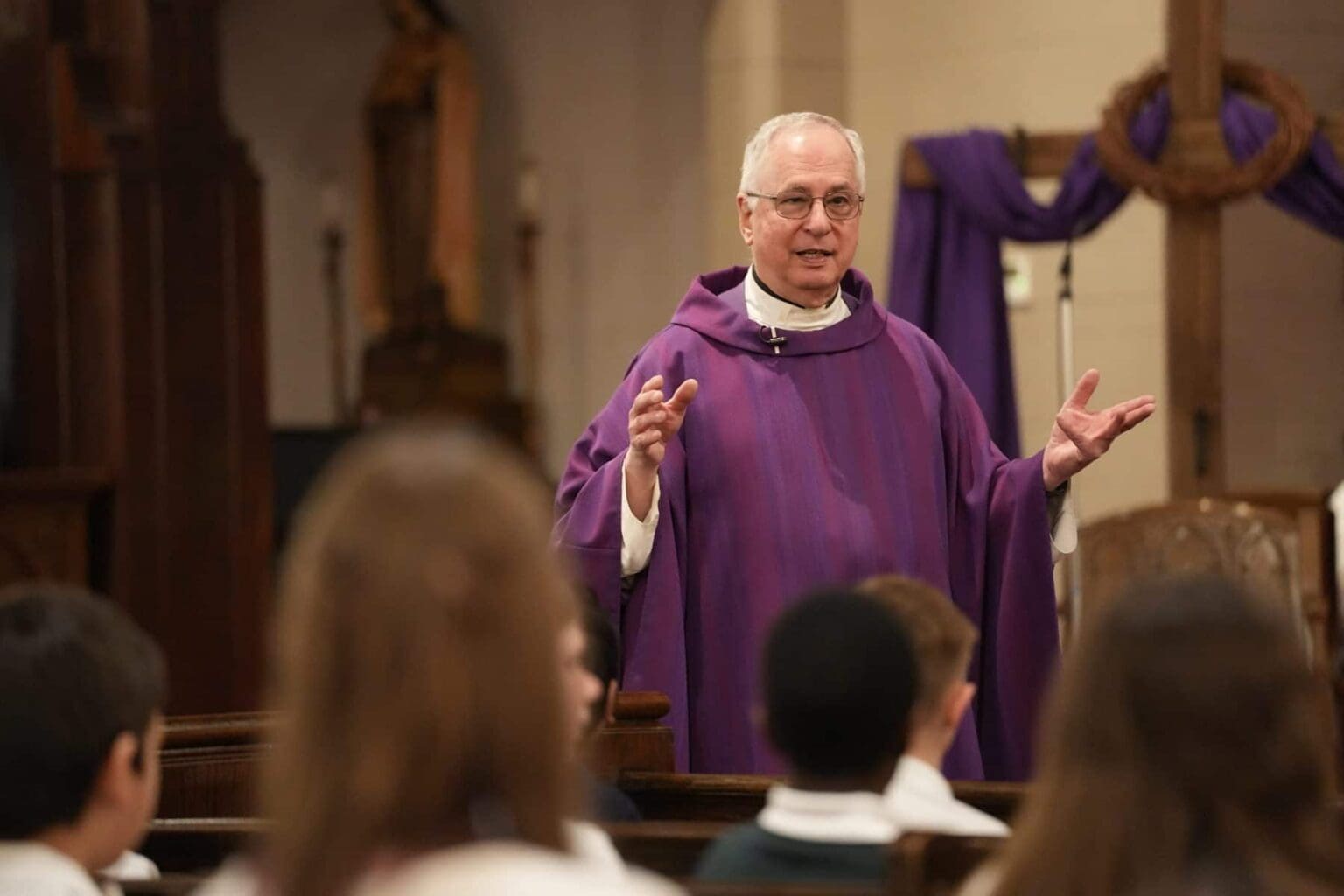 Clergyman in purple robe addressing a congregation during a church service, emphasizing community engagement.