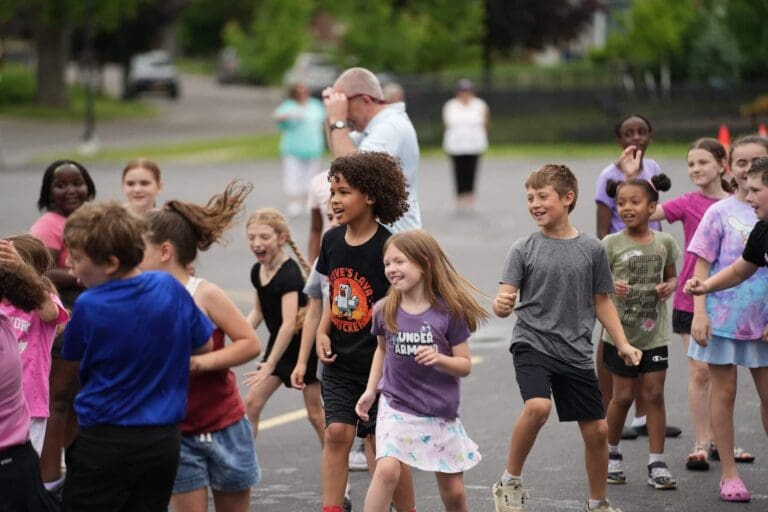Children playing joyfully outside during a summer camp activity.